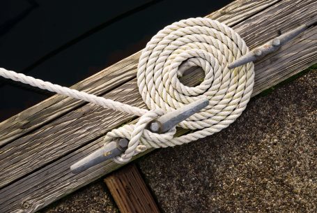 close up of rope wrapped around a metal adjustable hinge mounted on wood